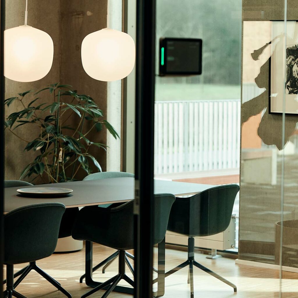 Mødelokale med glasvæg som er indrettet med moderne designermøbler i dansk design i rolige og neutrale farver.